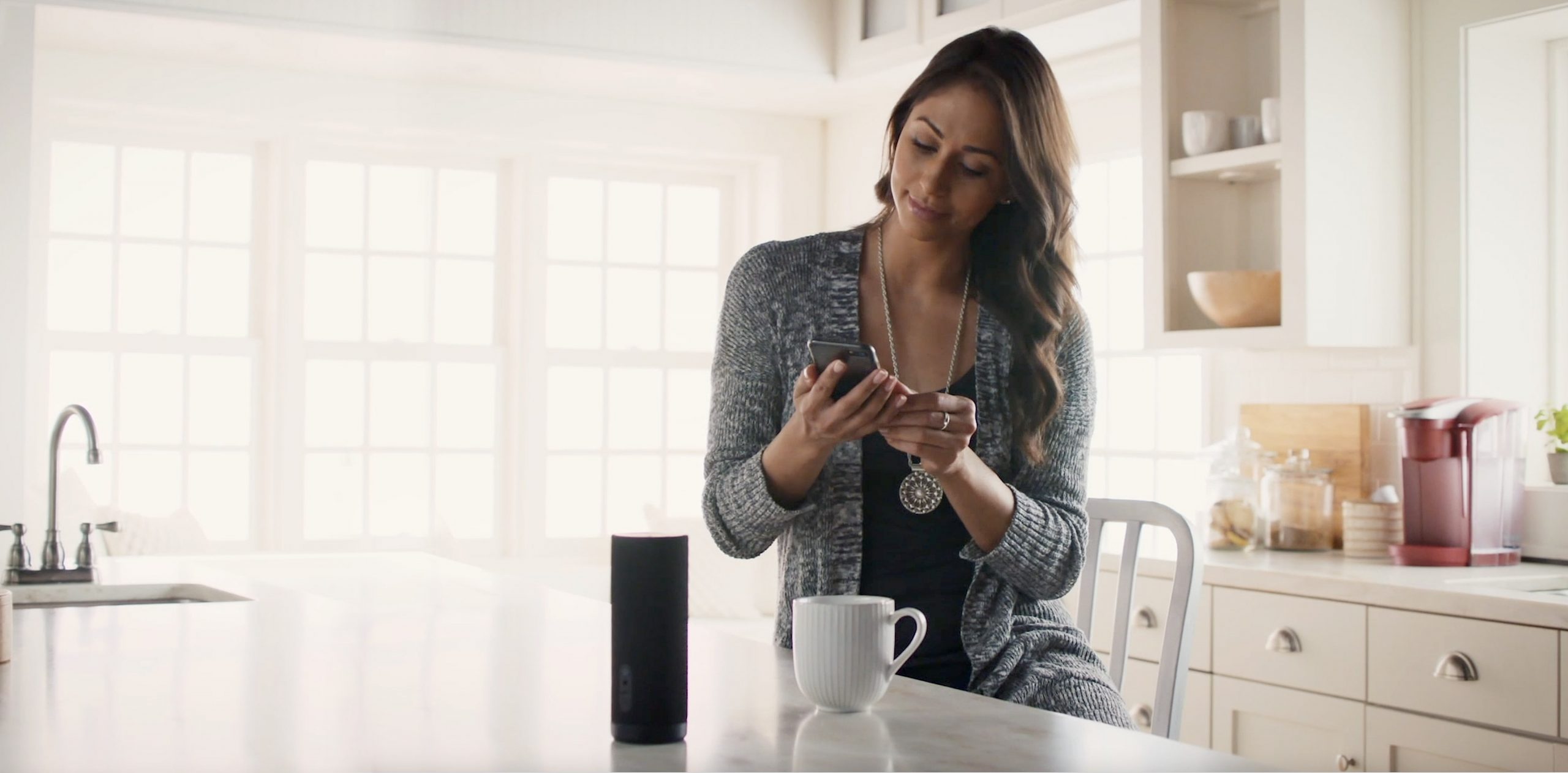 image of woman on her phone sitting at a counter with coffee